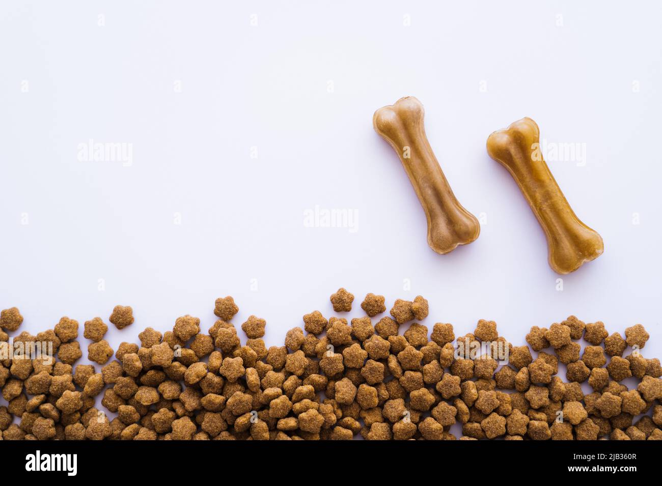 Draufsicht auf knochenförmige Leckereien in der Nähe von Tierfutter auf Weiß Stockfoto