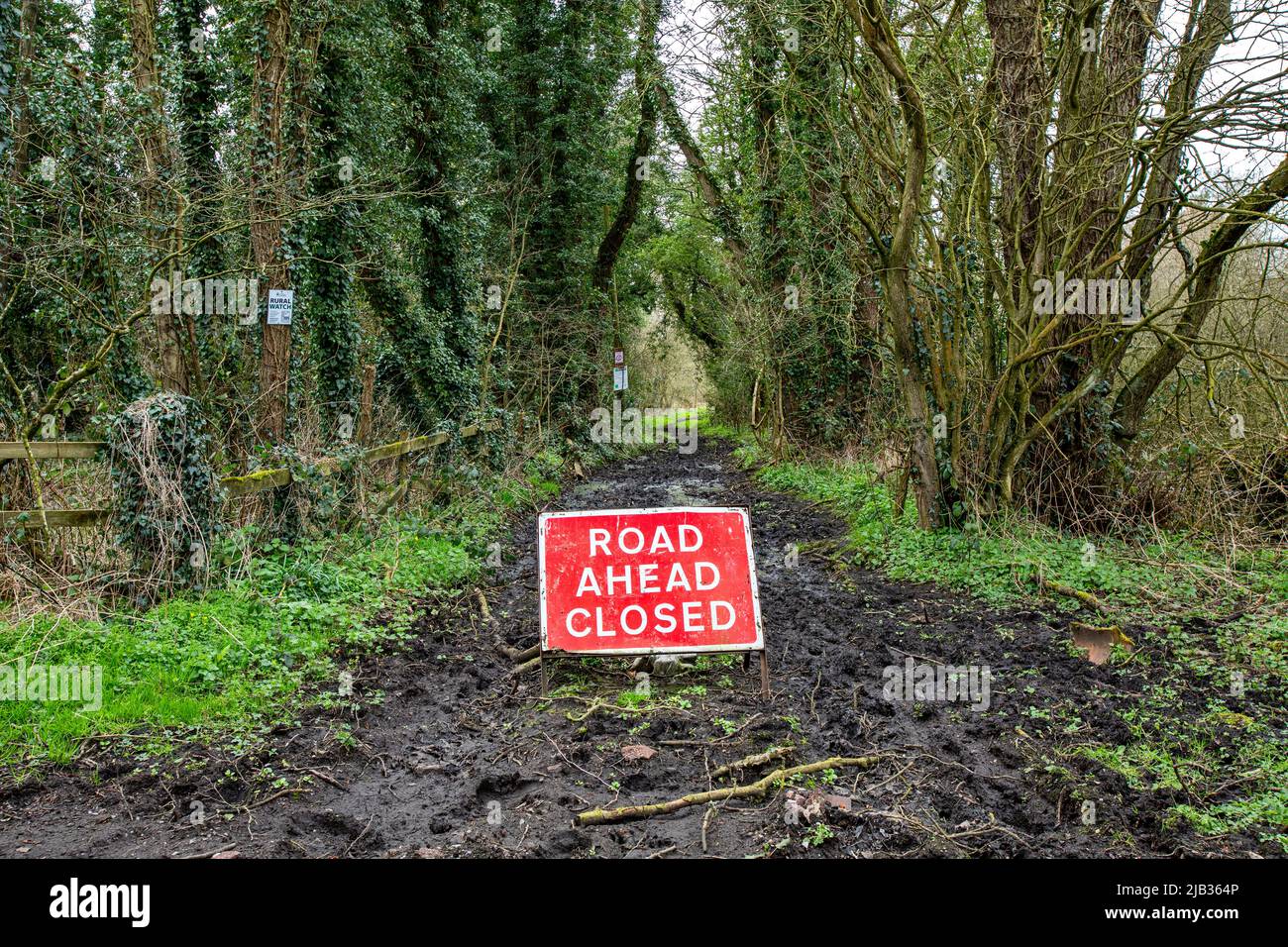 Straße vor geschlossenes Verkehrswarnschild auf schlammiger Straße in der Landschaft von Hes Stockfoto