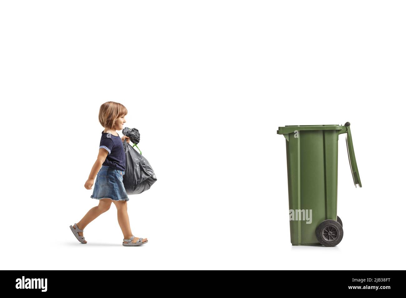 In voller Länge aufgenommen, wie ein kleines Mädchen auf einen Mülleimer zugeht und einen Abfallbeutel trägt, der isoliert auf weißem Hintergrund liegt Stockfoto