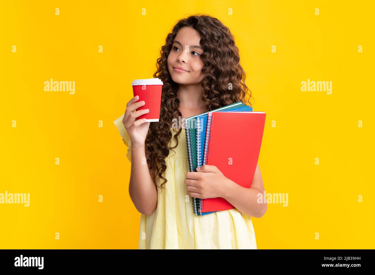 Morgen vor der Schule. Student teen Mädchen mit Büchern halten Takeaway Lieferung Tasse Kaffee auf gelbem Hintergrund isoliert. Bildung in College-Konzept Stockfoto