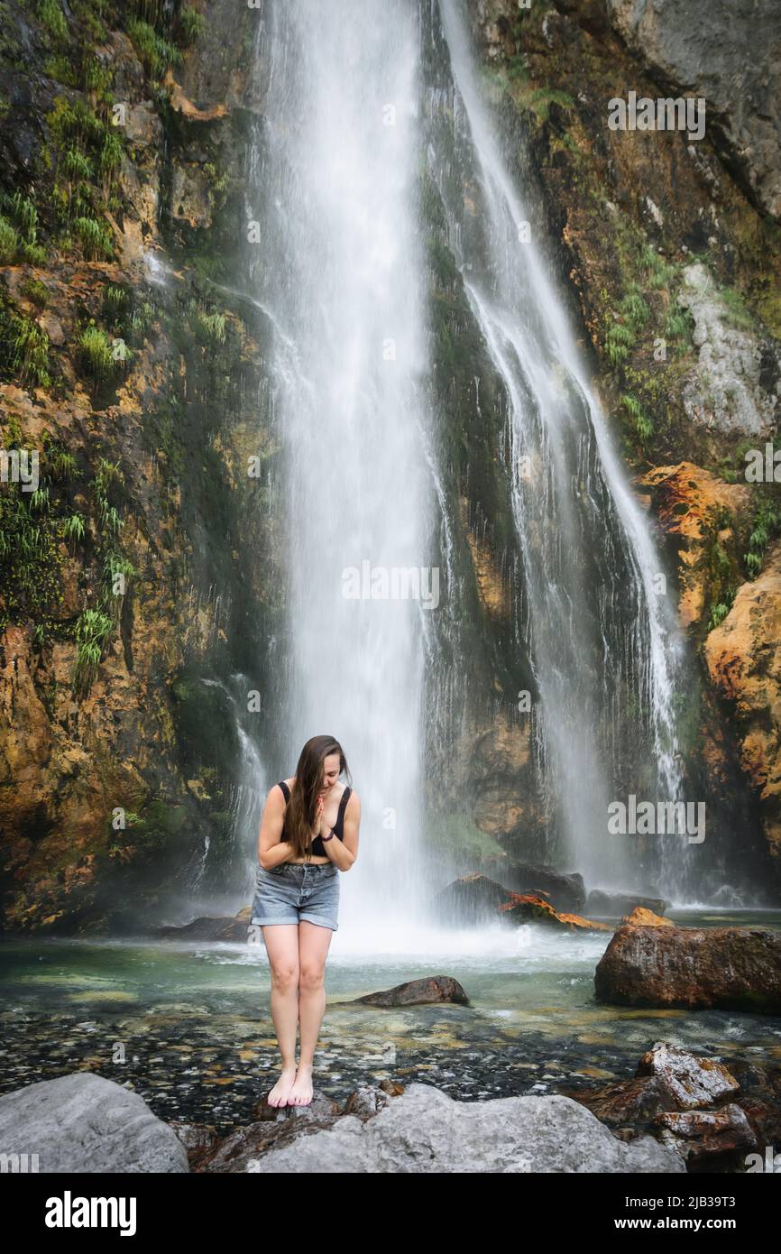 Das kalte, eisige Wasser eines alpinen Wasserfalls unter dem Mount Goverla erfrischt sich nach einem heißen Tag. Gesunde schöne Mädchen badet in schnellen Strömen eines sauberen s Stockfoto