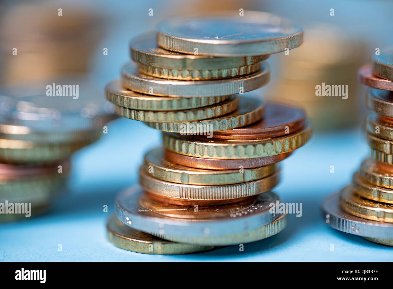 Euro-Münzen zu Türmen aufgeschichtet. Münzen auf blauem Hintergrund. EUR-Währung aus der Europäischen Union Stockfoto