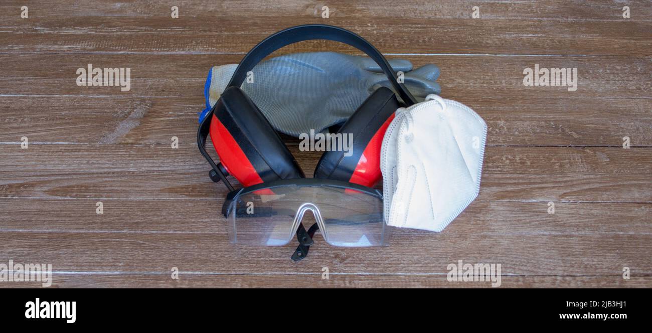 Abbildung von Handschuhen, Brille, Kopfhörern, Gesichtsmaske und einer erste-Hilfe-Box. Darstellung von Arbeitsunfällen Stockfoto