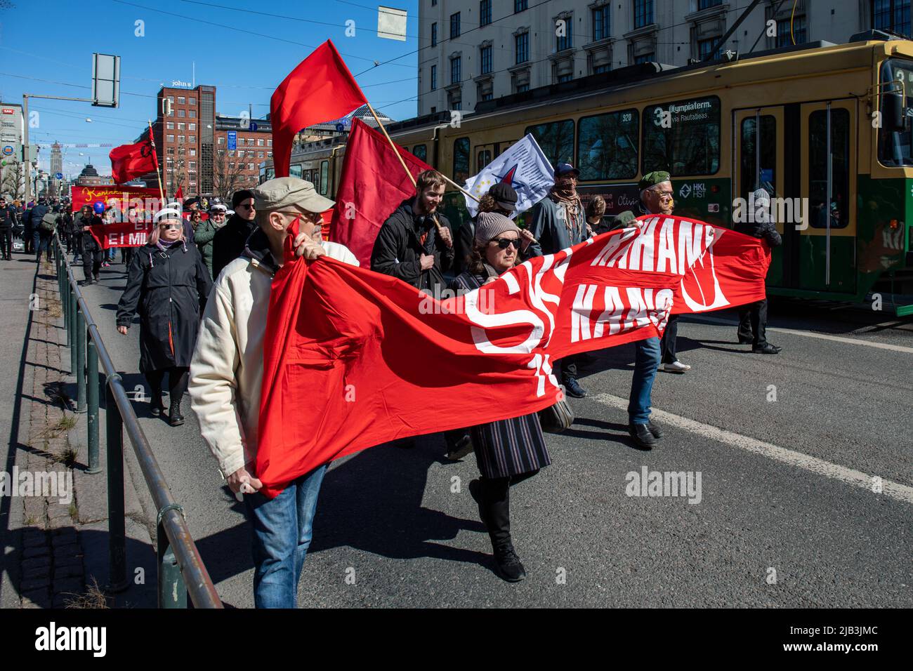 Menschen, die ein rotes Banner in der Hand halten und an der sozialistischen Parade zum 1. Mai beim Internationalen Arbeitertag in Helsinki, Finnland, teilnehmen Stockfoto