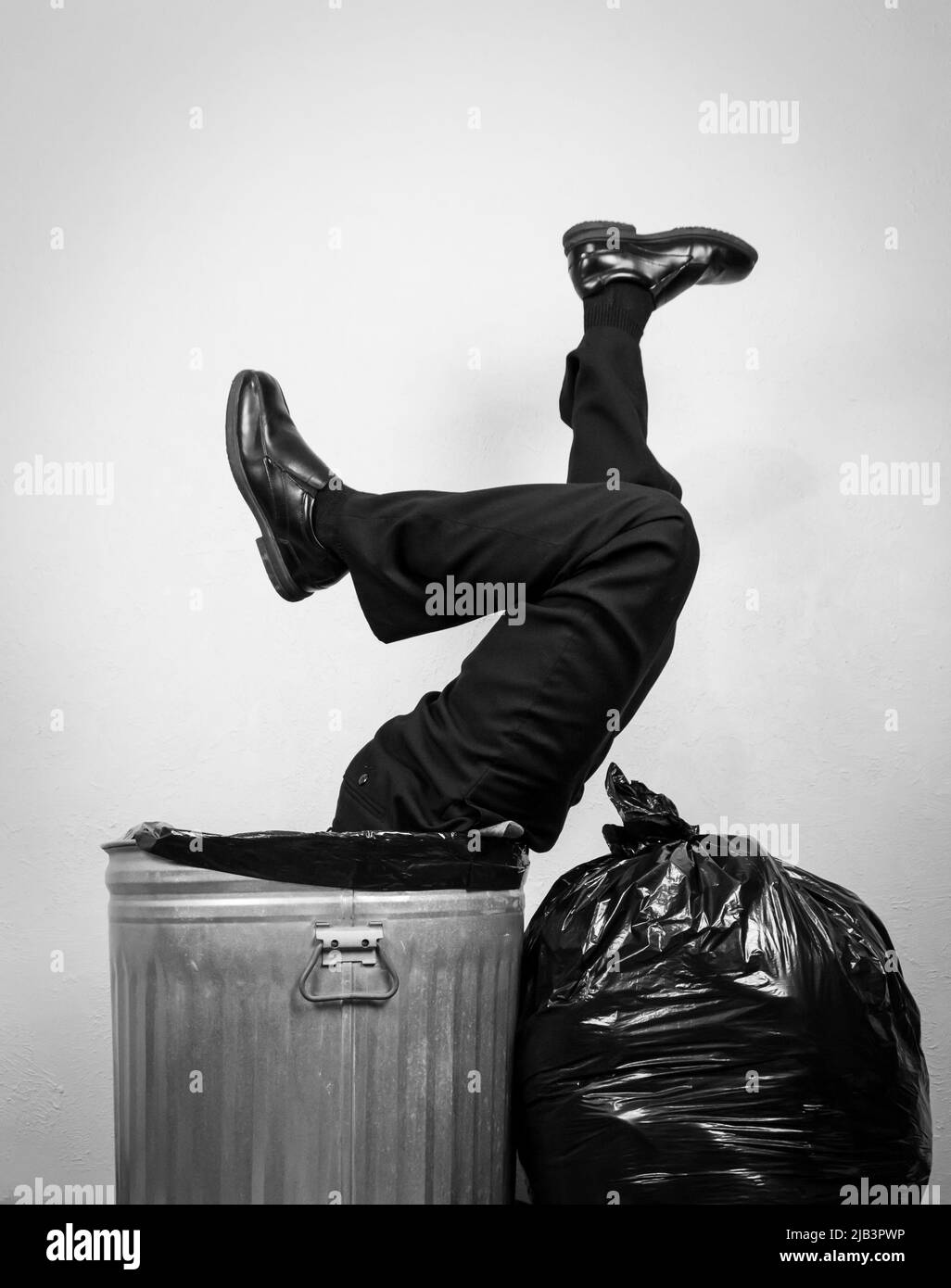 Geschäftsmann in Anzug in Trash Can stecken. Konzept von über einem Barrel. Wasted Life Wird Weggeworfen Stockfoto