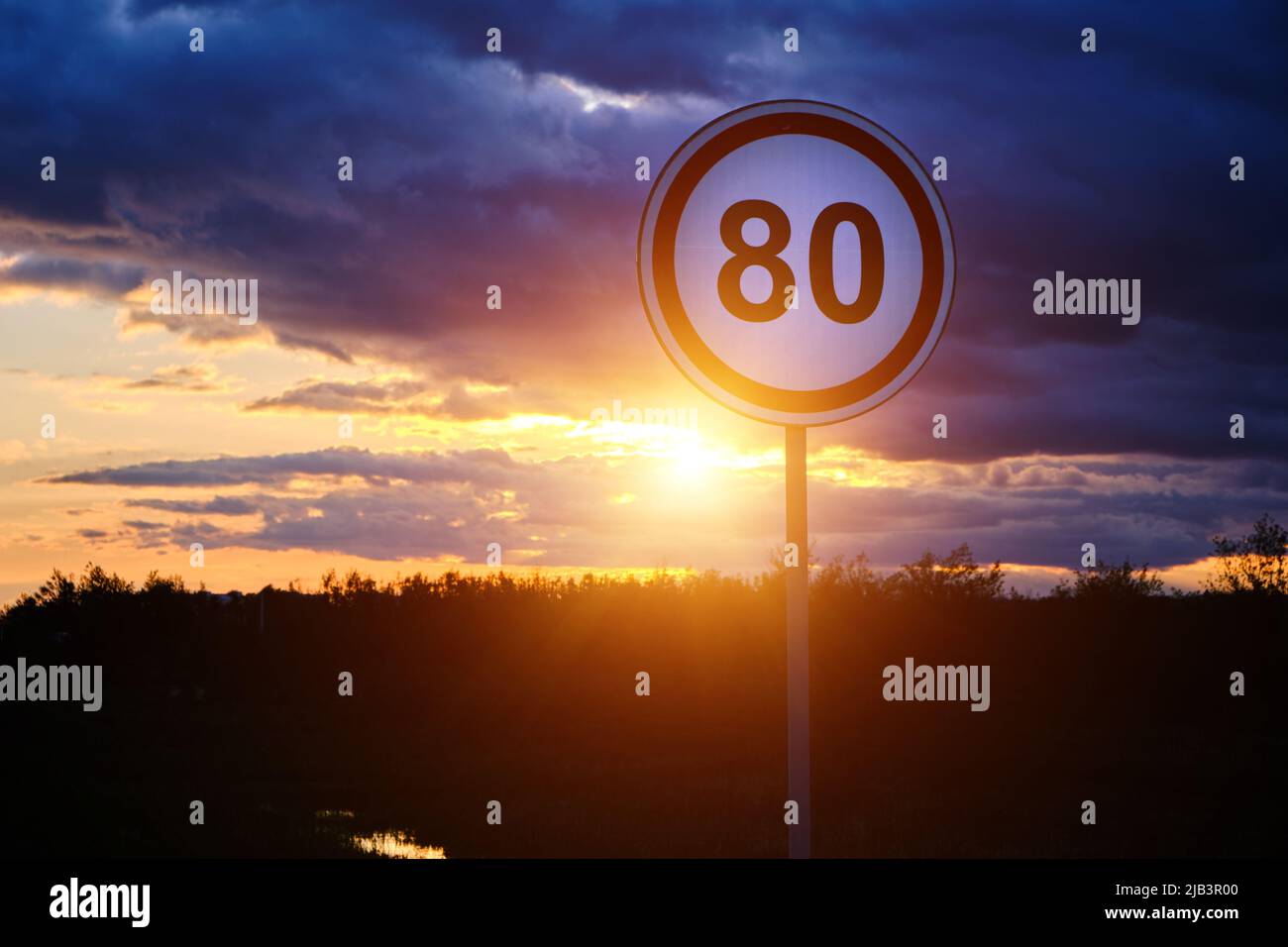 Geschwindigkeitsbegrenzungszeichen von 80 km h Hintergrund heller Sonnenuntergang und Wolken Stockfoto