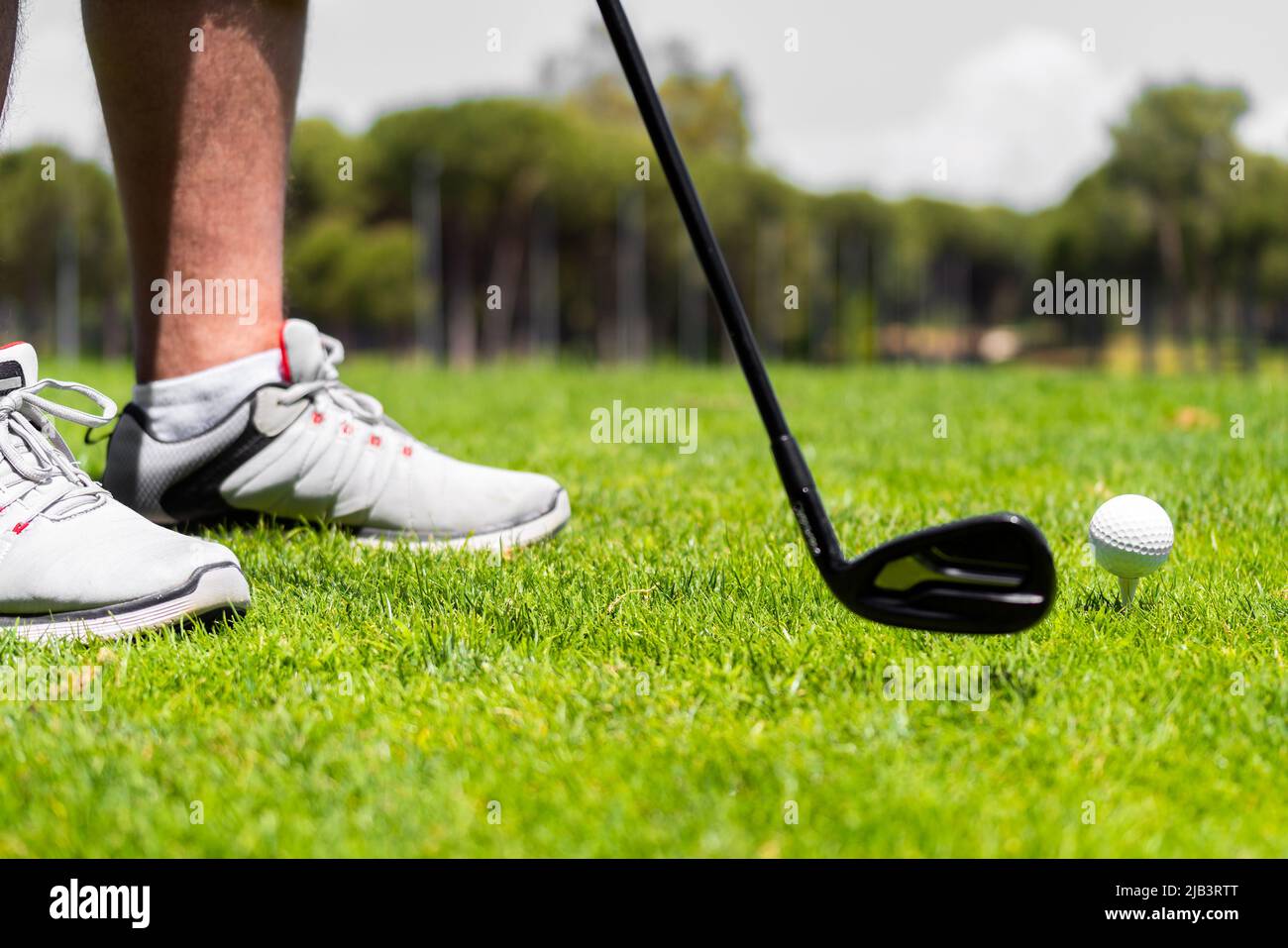 Mann, der mit einem eisernen Golfschläger steht, bereit, auf dem Golfplatz einen Ball auf grünem Gras zu schlagen Stockfoto