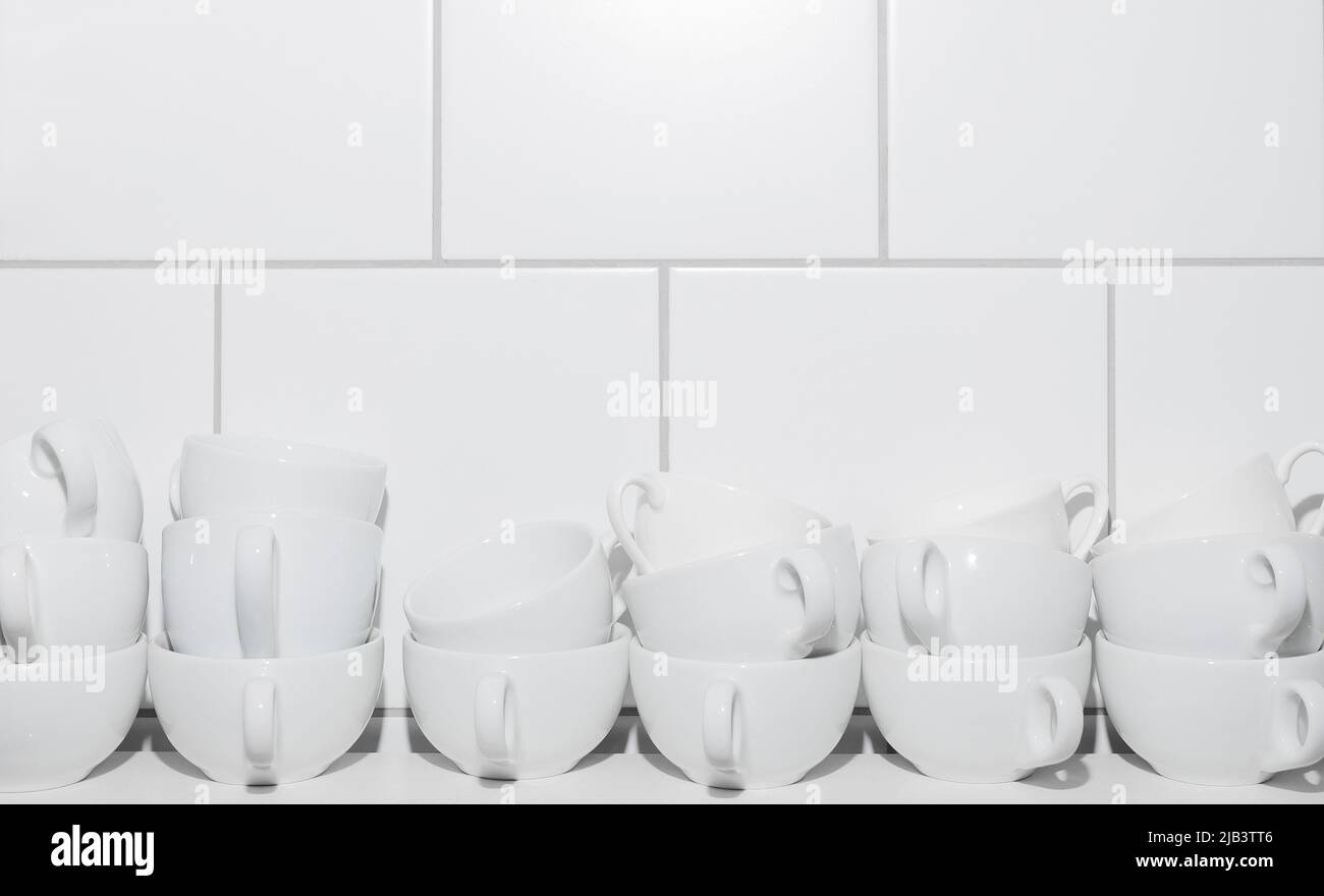 In zwei Reihen von weißen Tassen auf einem weißen Tisch auf einem Hintergrund aus weißen Fliesen. Speicherplatz kopieren Stockfoto