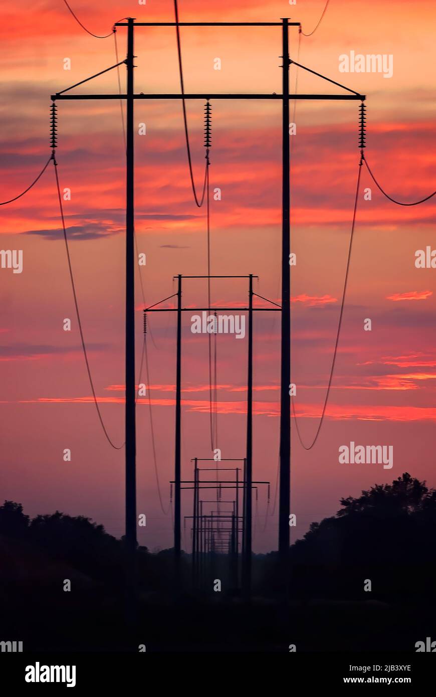 Die hölzernen Hochspannungsmasten mit H-Rahmen sind bei Sonnenuntergang am 13. Juni 2011 in Columbus, Mississippi, abgebildet. Stockfoto