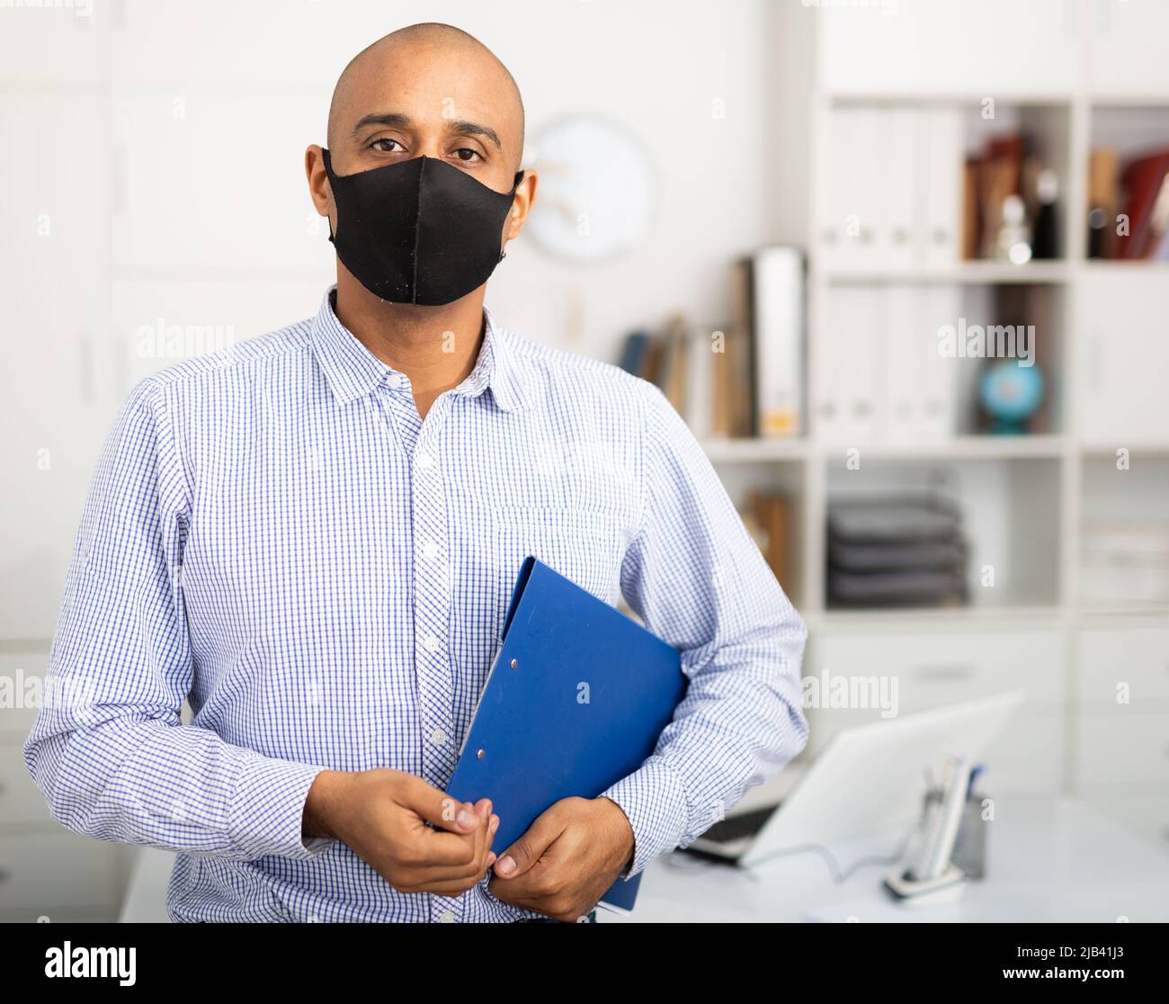 Porträt eines positiven Geschäftsmanns in Schutzmaske mit Dokumentenmappe Stockfoto