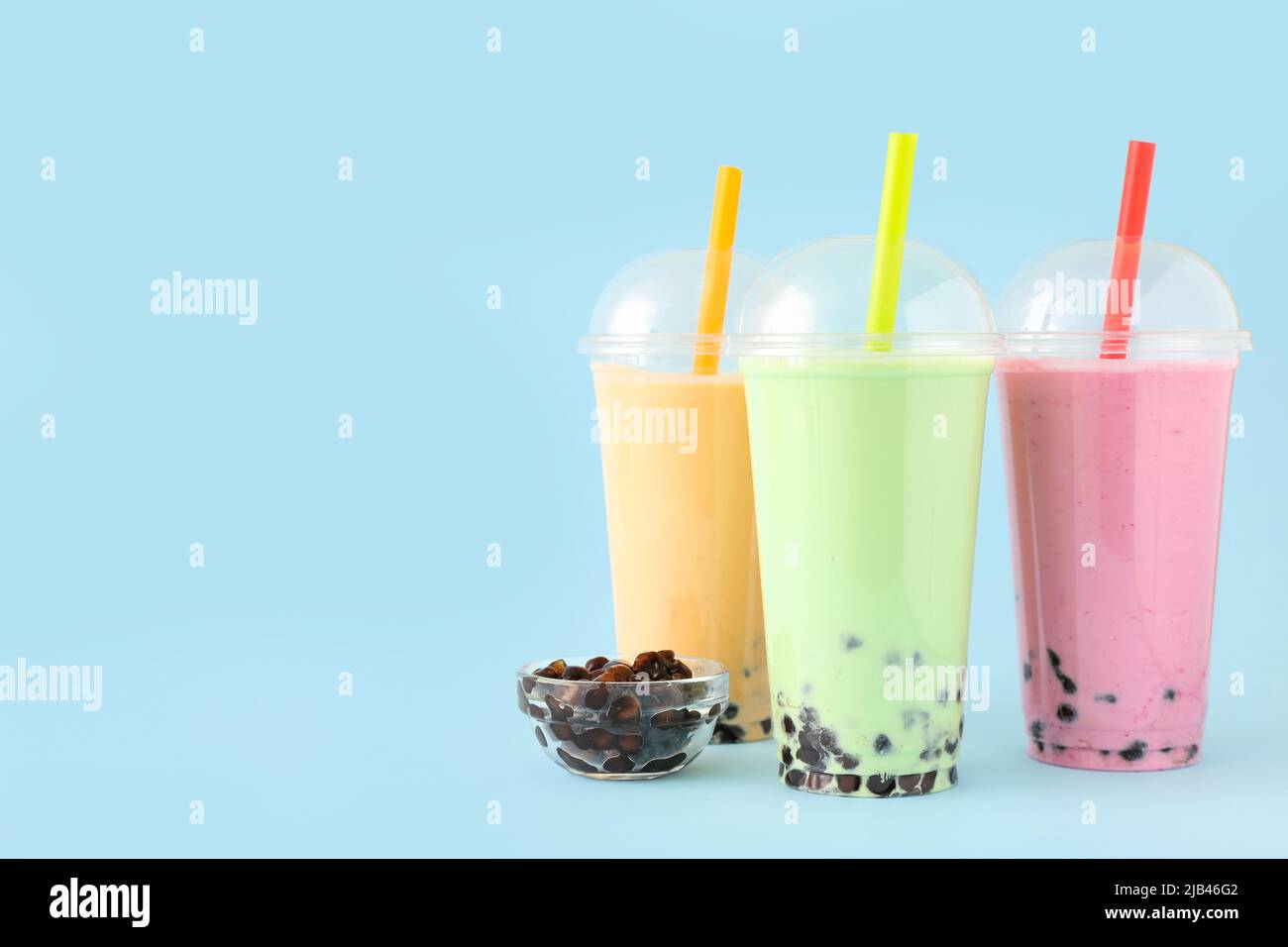 Plastikbecher mit verschiedenen leckeren Bubble Tea auf blauem Hintergrund Stockfoto