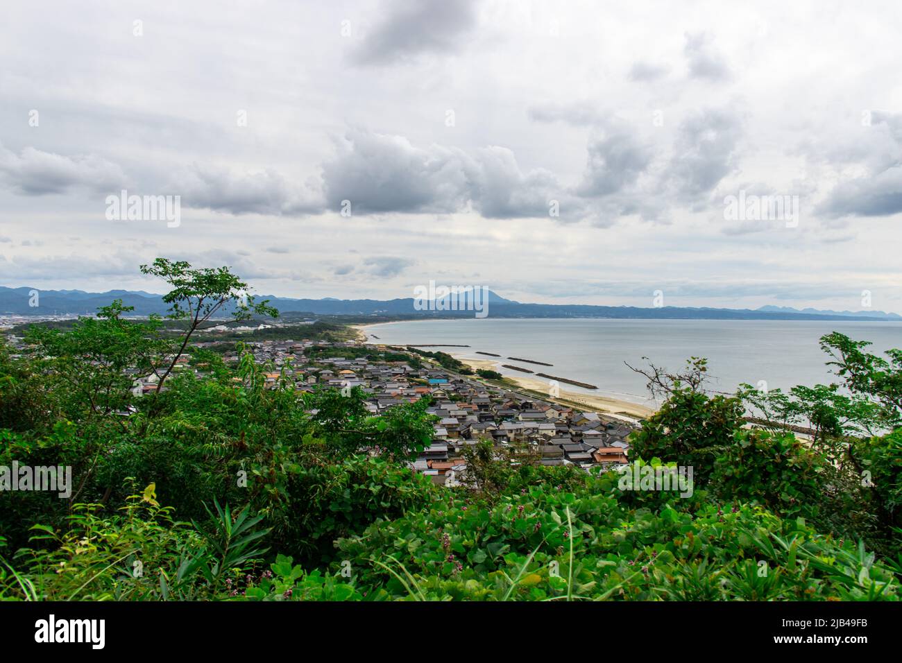 Landschaft von Izumo Stadt und Strand von der Hügelspitze am Mt. Hounouzan Park, Shimane in Japan, an bewölkten Tagen. In der Ferne befindet sich der Inasa-Strand (Bentenjima) Stockfoto