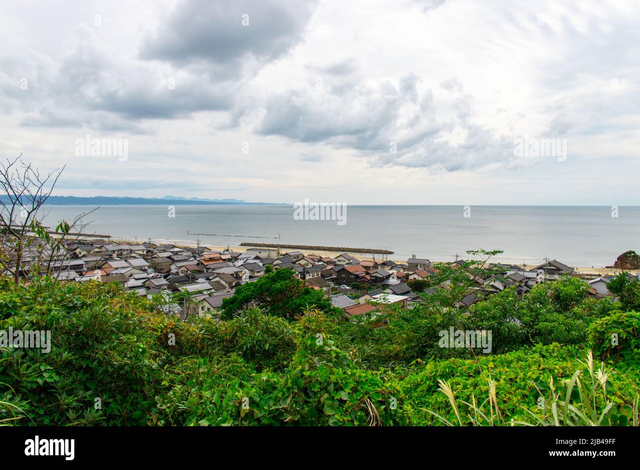 Landschaft von Izumo Stadt und Strand von der Hügelspitze am Mt. Hounouzan Park, Shimane in Japan, an bewölkten Tagen. In der Ferne befindet sich der Inasa-Strand (Bentenjima) Stockfoto