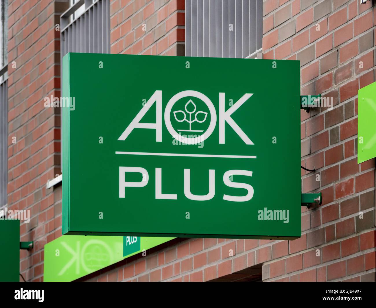 AOK PLUS Logo auf einer Gebäudefassade. Eine große deutsche Krankenkasse. Gesetzlich vorgeschriebener Dienst zur Prävention von Erkrankungen der Gesellschaft in Sachsen. Stockfoto