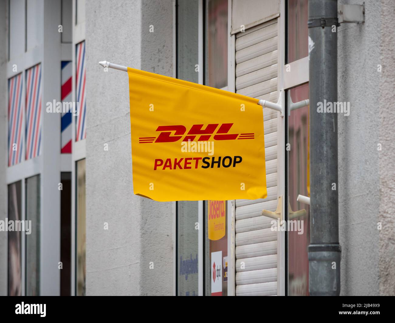 DHL Paketshop in der Stadt. An der Außenseite eines Geschäftsgebäudes hängt eine kleine gelbe Fahne. Das Logo bedeutet, dass die Menschen versenden und empfangen können Paket Stockfoto