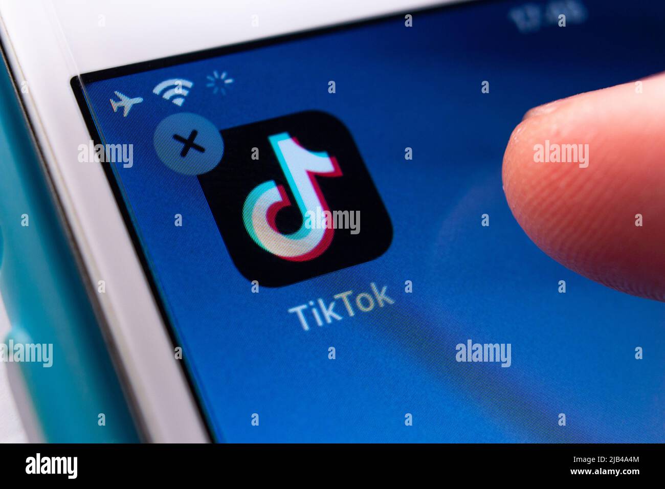 Mann Hand über Tippen und löschen TikTok App auf dem iPhone. TikTok ist eine chinesische Video-App für soziale Medien, mit der kurze Videos von Bytedance erstellt und geteilt werden können Stockfoto