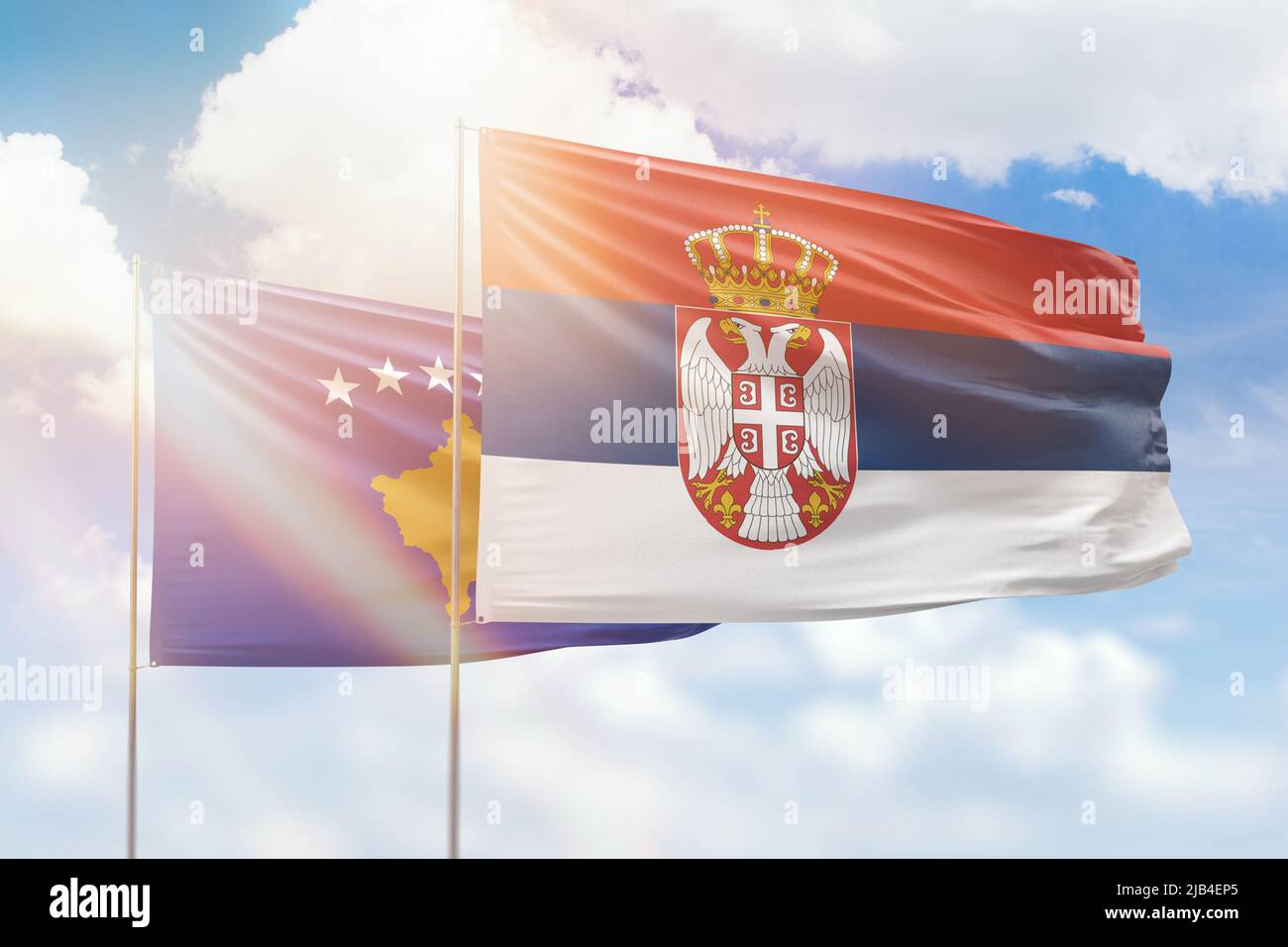 Sonniger blauer Himmel und Flaggen von serbien und kosovo Stockfoto