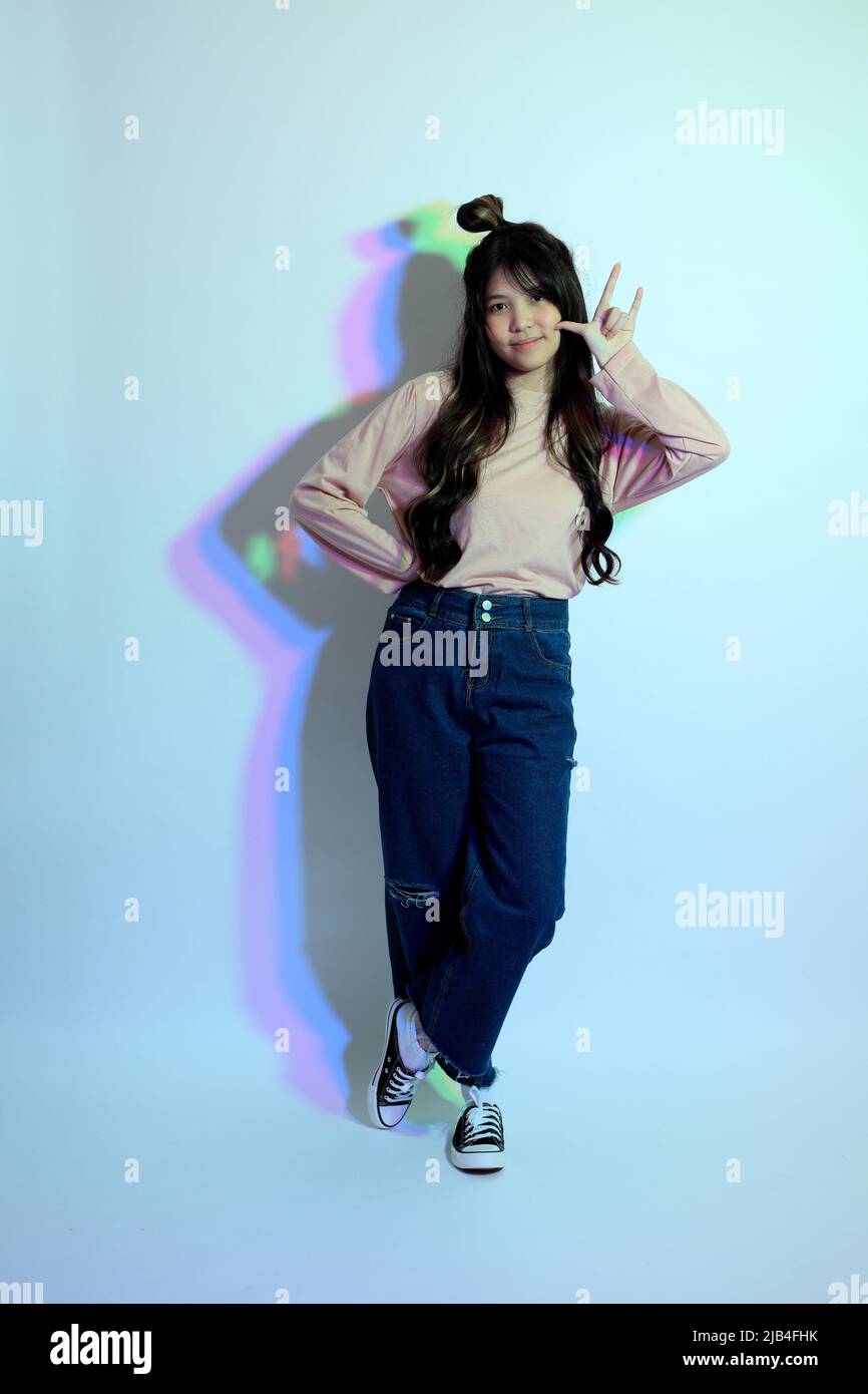 Die niedlichen jungen asiatischen Mädchen mit lässigen Kleidung posiert unter der Gel-Farbe Blitz im Studio. Stockfoto