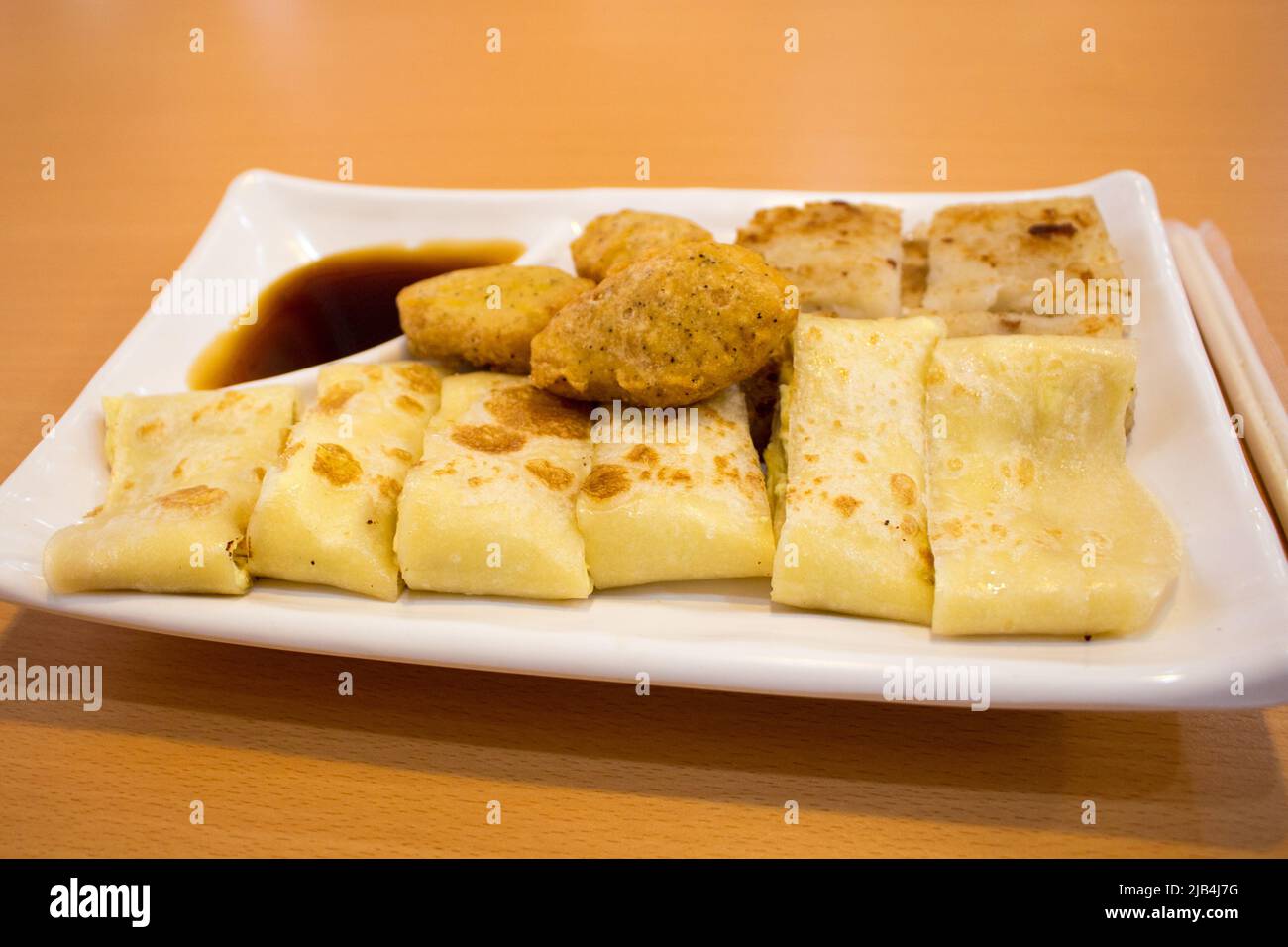 Das taiwanesische Frühstück (taiwanesischer Eierpfannkuchen, Rettichkuchen, Hühnchen-Nugget und Quelle) auf dem Teller im Restaurant in Taipei, Taiwan. Stockfoto