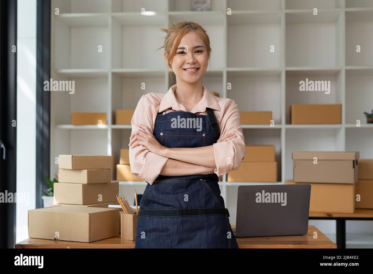 Porträt einer vertraulichen asiatischen Frau Kellnerin Schürze stand bei ihr zu Hause mit Pappe für den Versand Online-Shopping Kleinunternehmen Inhaber Konzept. Stockfoto