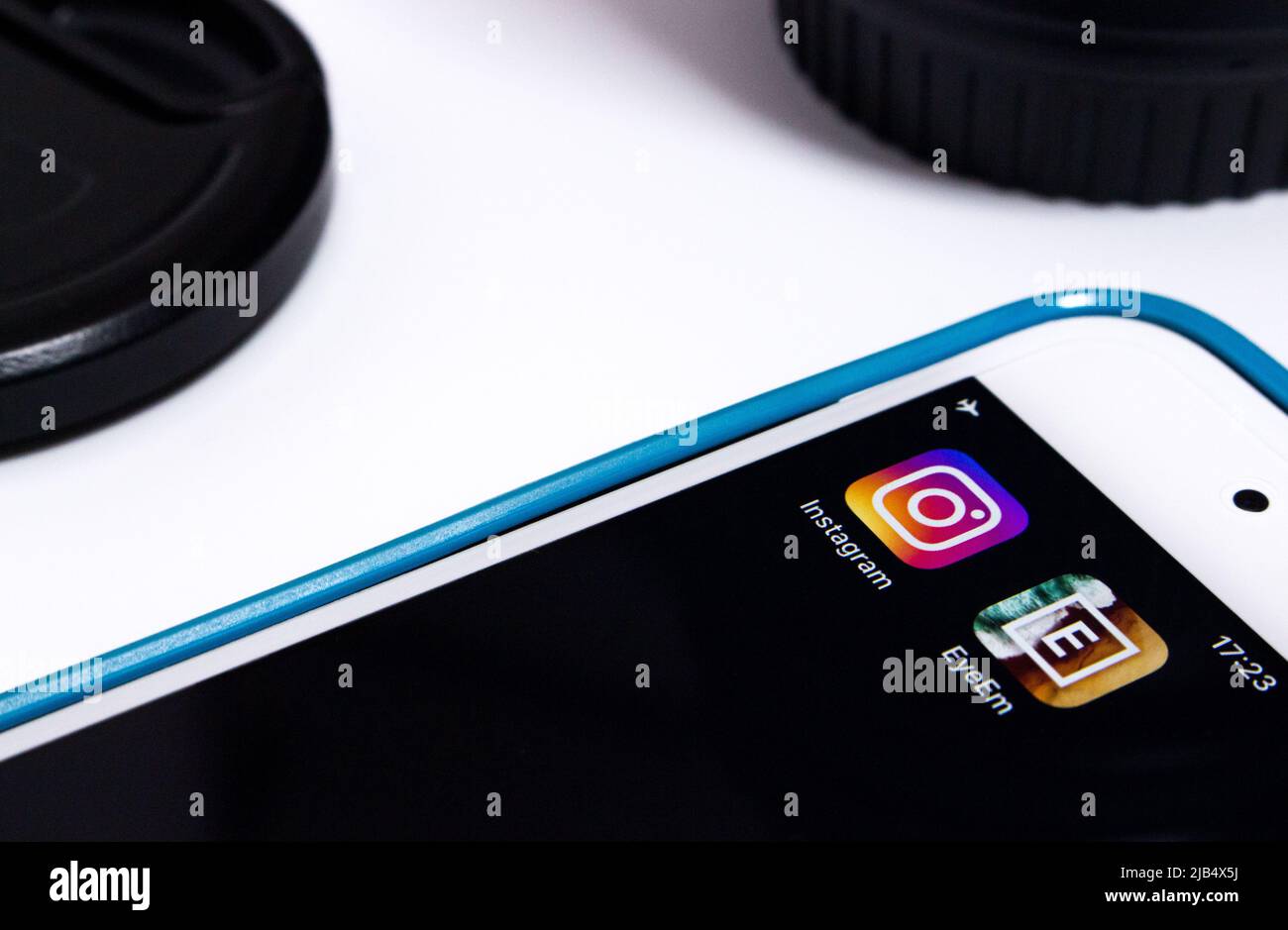 Instagram & EyeEM auf dem iPhone mit Kameraobjektiv und Kappe. EyeEm ist ein Technologieunternehmen mit einer globalen Fotografie-Community und einem Marktplatz mit Sitz in Berlin Stockfoto