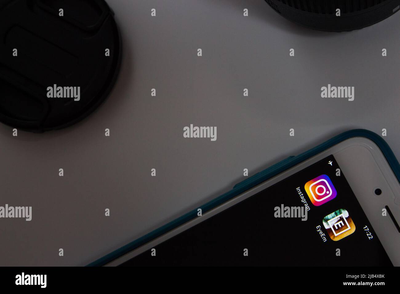 Instagram & EyeEM auf dem iPhone mit Kameraobjektiv und Kappe. EyeEm ist ein Technologieunternehmen mit einer globalen Fotografie-Community und einem Marktplatz mit Sitz in Berlin Stockfoto