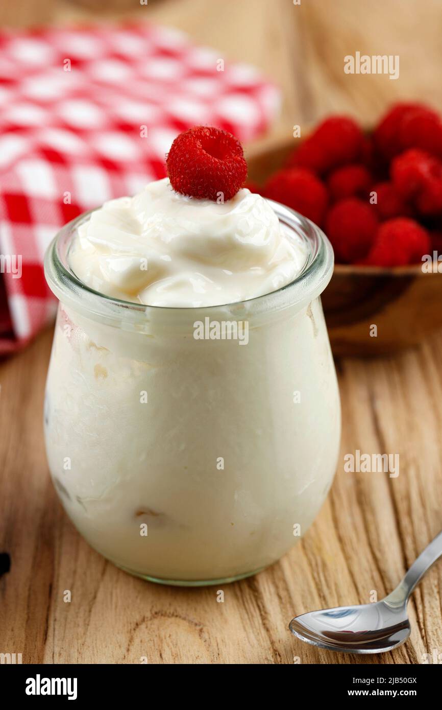 Ein Glas Joghurt mit wilden Himbeeren auf einem Holztisch Stockfoto
