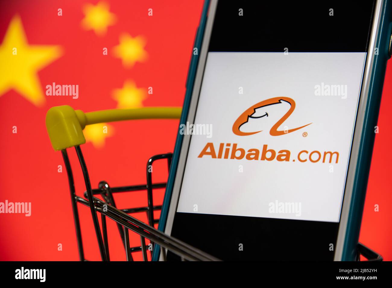 Alibaba.com Logo auf iPhone im Warenkorb mit chinesischer Flagge. Die Alibaba Group, China, ist das weltweit größte Einzelhandelsunternehmen und E-Commerce-Unternehmen Stockfoto