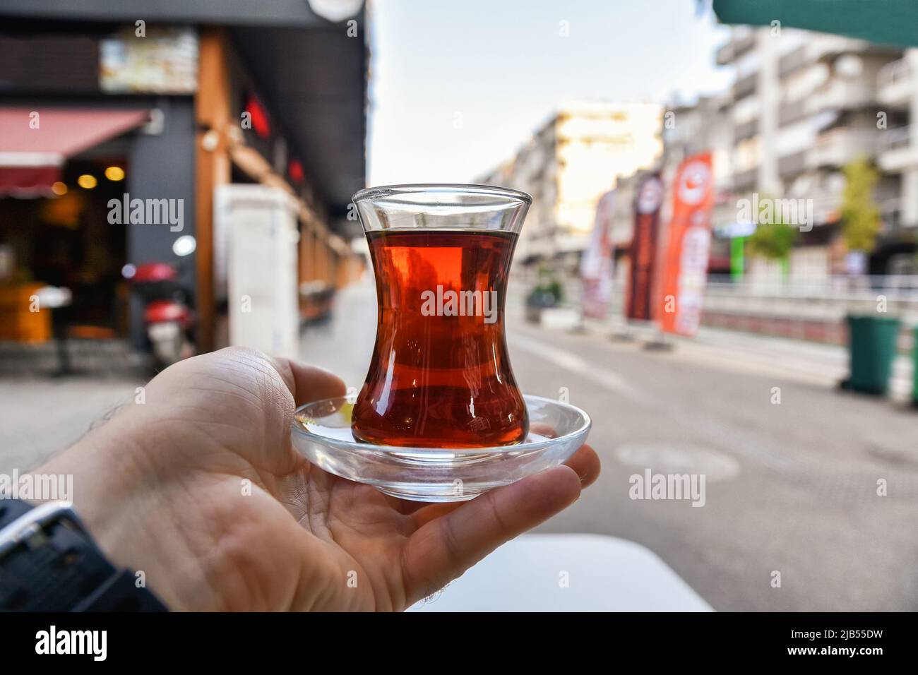 Tasse türkischer Tee in der Hand. Straßen von morgens Antalya, schwarzer Tee. Stockfoto