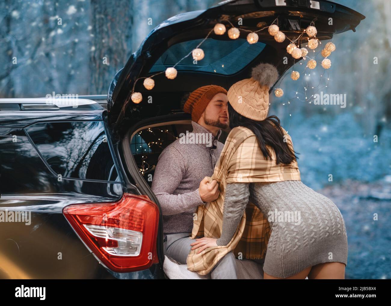 Paar mit Datum und sitzen im Auto in Winterkleidung im Schnee Wald Stockfoto