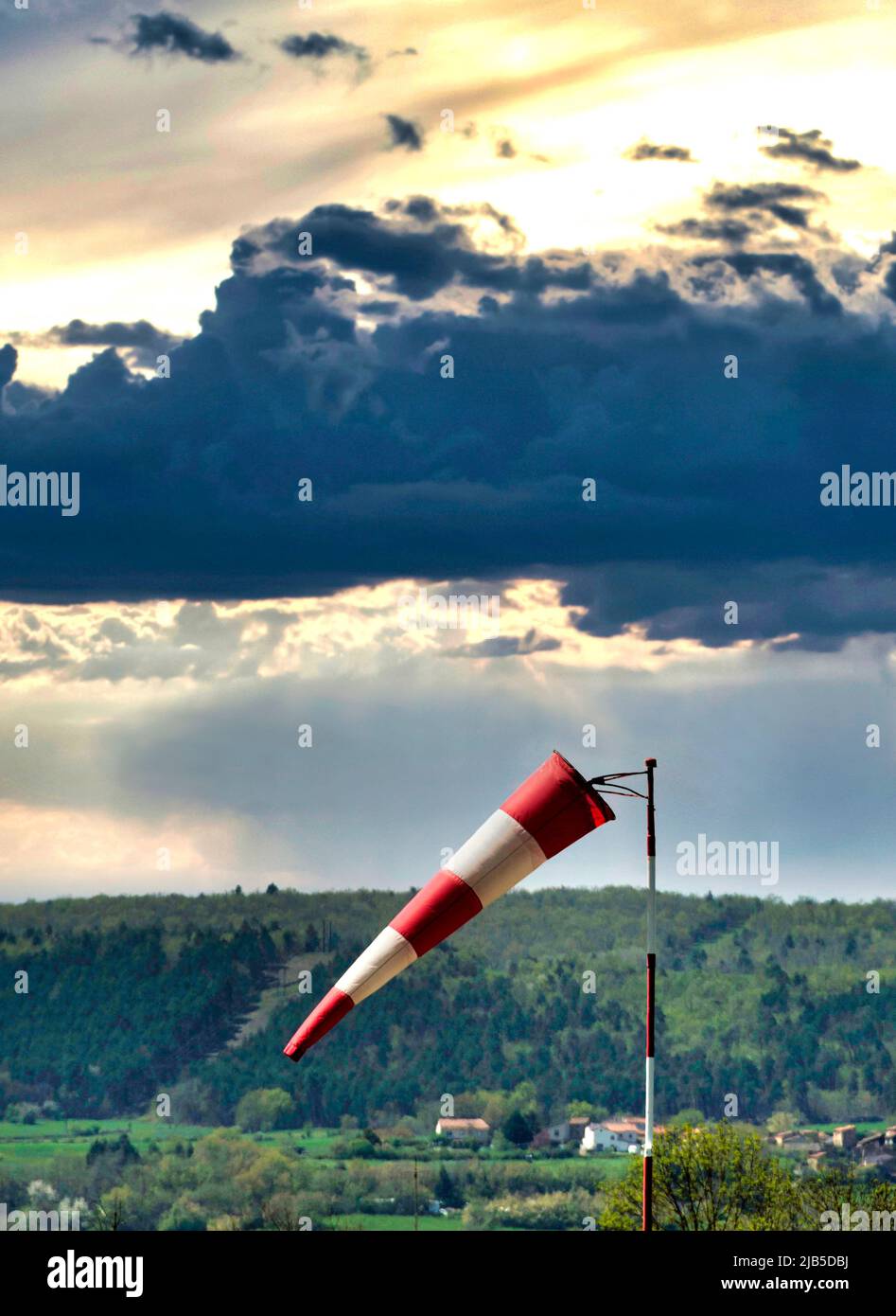 Windrichtungsanzeiger in der Nähe einer Landschaft bei Sonnenuntergang mit dramatischen Wolkenformationen Stockfoto