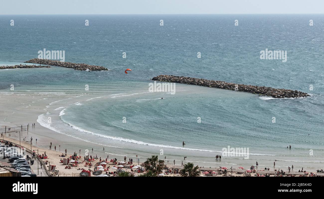 Blick auf den Strand und das Wellenbrecher von Netanya in Israel am östlichen Mittelmeer, wo Menschen schwimmen, wandern und Kitesurfen Stockfoto