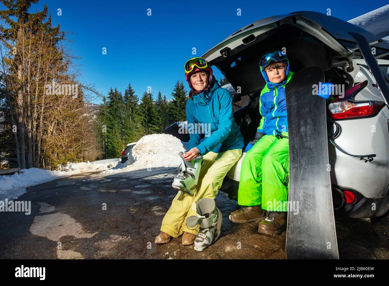 Familie legt Ski- und Snowboardschuhe auf dem Parkplatz an Stockfoto