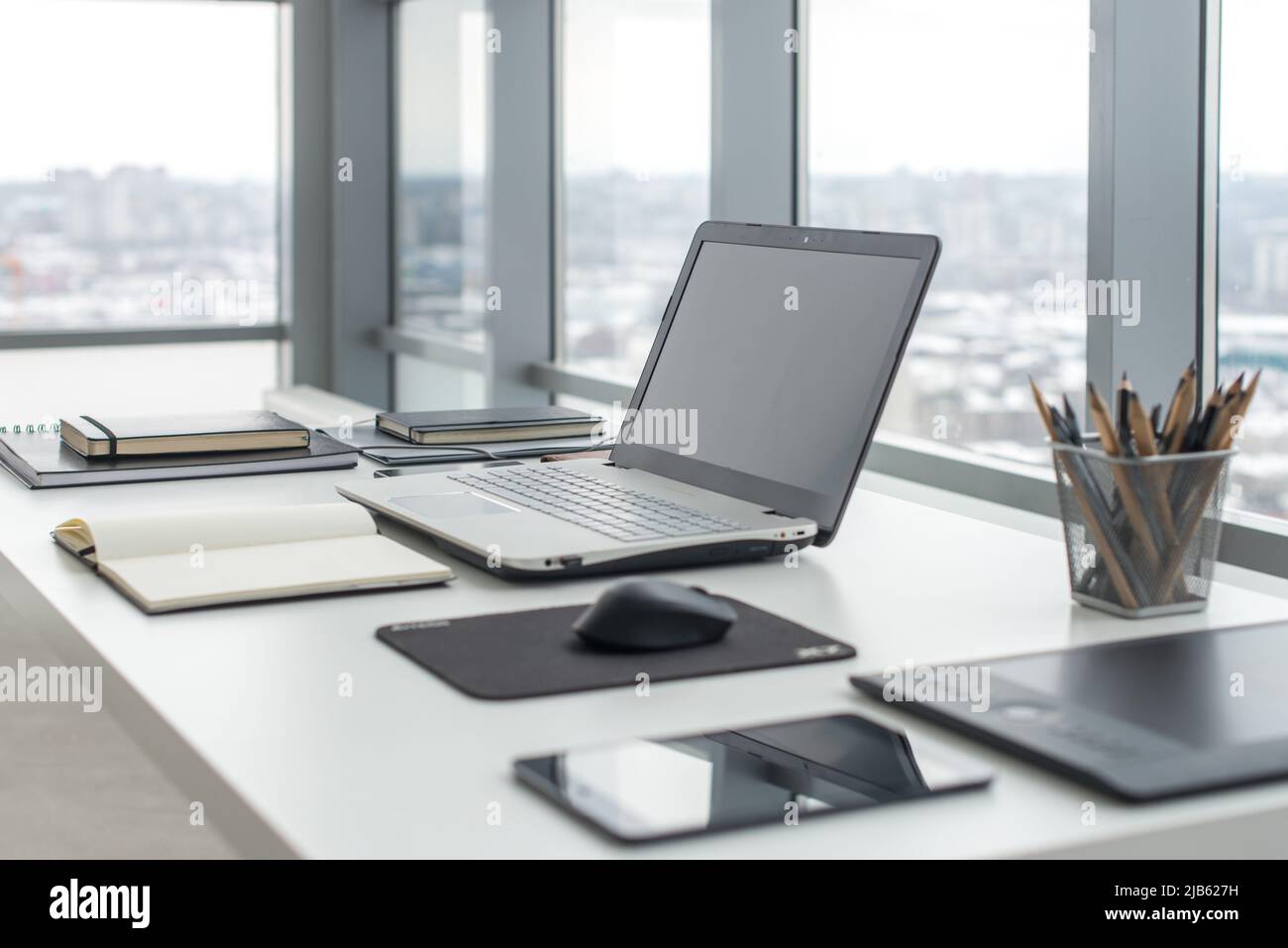 Arbeitsplatz mit Notebook Laptop komfortabler Arbeitstisch im Büro mit fenster und Blick auf die Stadt Stockfoto