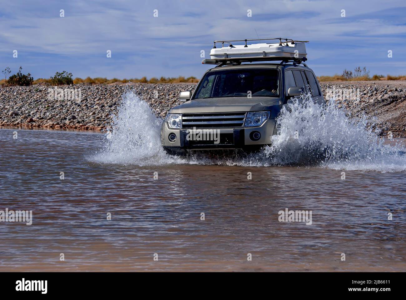 Jeep Land Rover Geländewagen, der durch die marokkanische Wüste fährt und in einen Pool aus Wasser steigt. Stockfoto