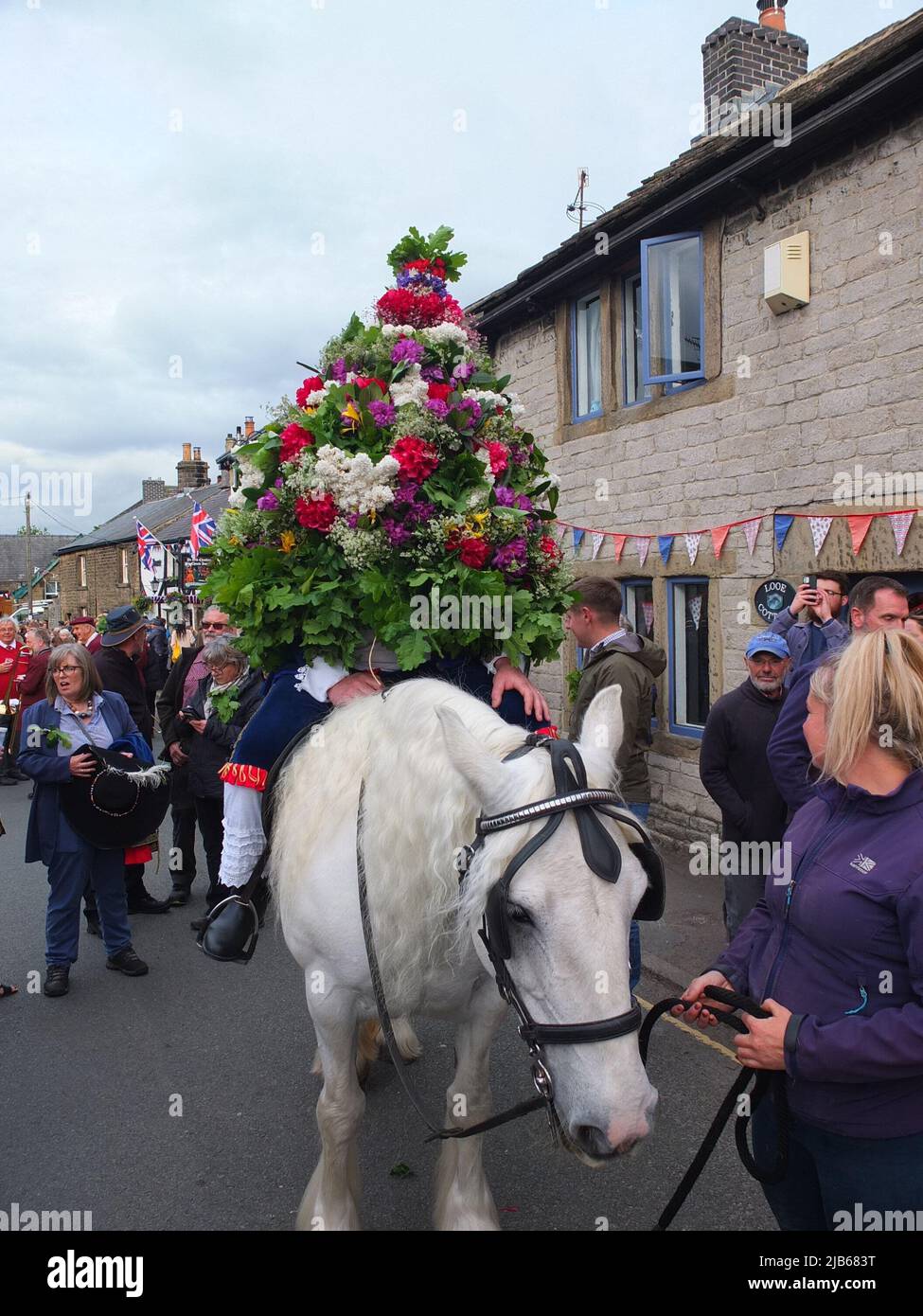 Der König der Castleton Garland mit einem Kranz aus Blumen reitet zu Pferd durch das Dorf während der alten Castleton Garland Ceremony 2022 Stockfoto