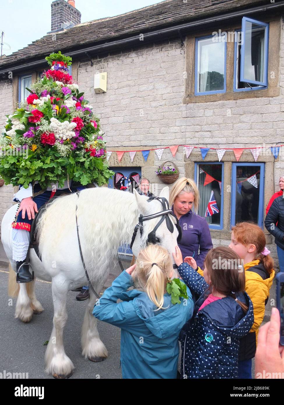 Der König der Castleton Garland mit einem Kranz aus Blumen reitet zu Pferd durch das Dorf während der alten Castleton Garland Ceremony 2022 Stockfoto