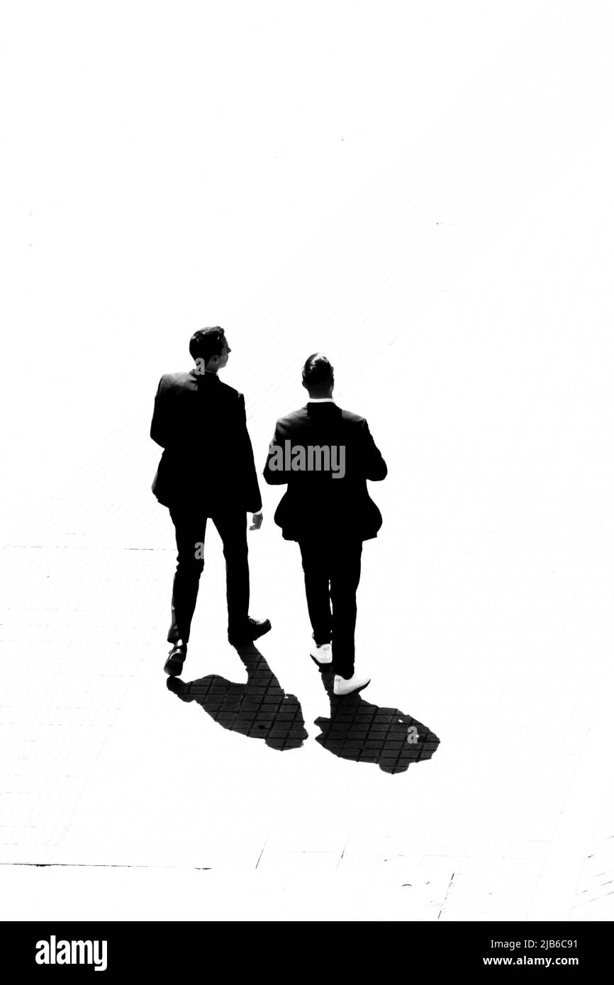 Zwei Männer in Geschäftsanzügen gehen draußen durch. Stockfoto
