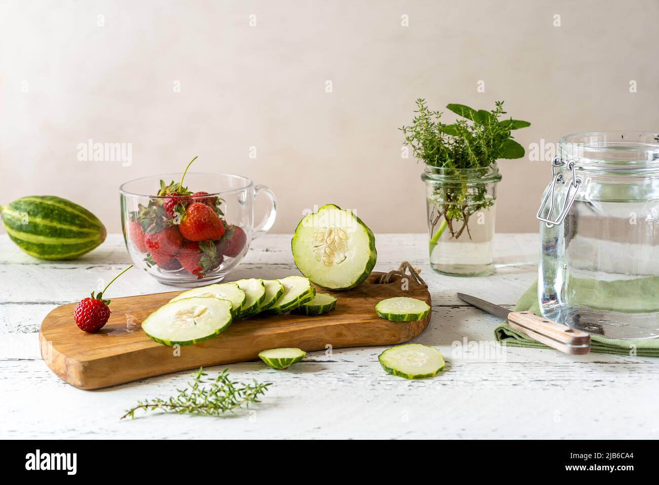 Zubereitung von infundierten Wasser mit Erdbeere und Meloncella, die eine Mischung aus Gurke und Melone, Thymian, Minze ist. Stockfoto