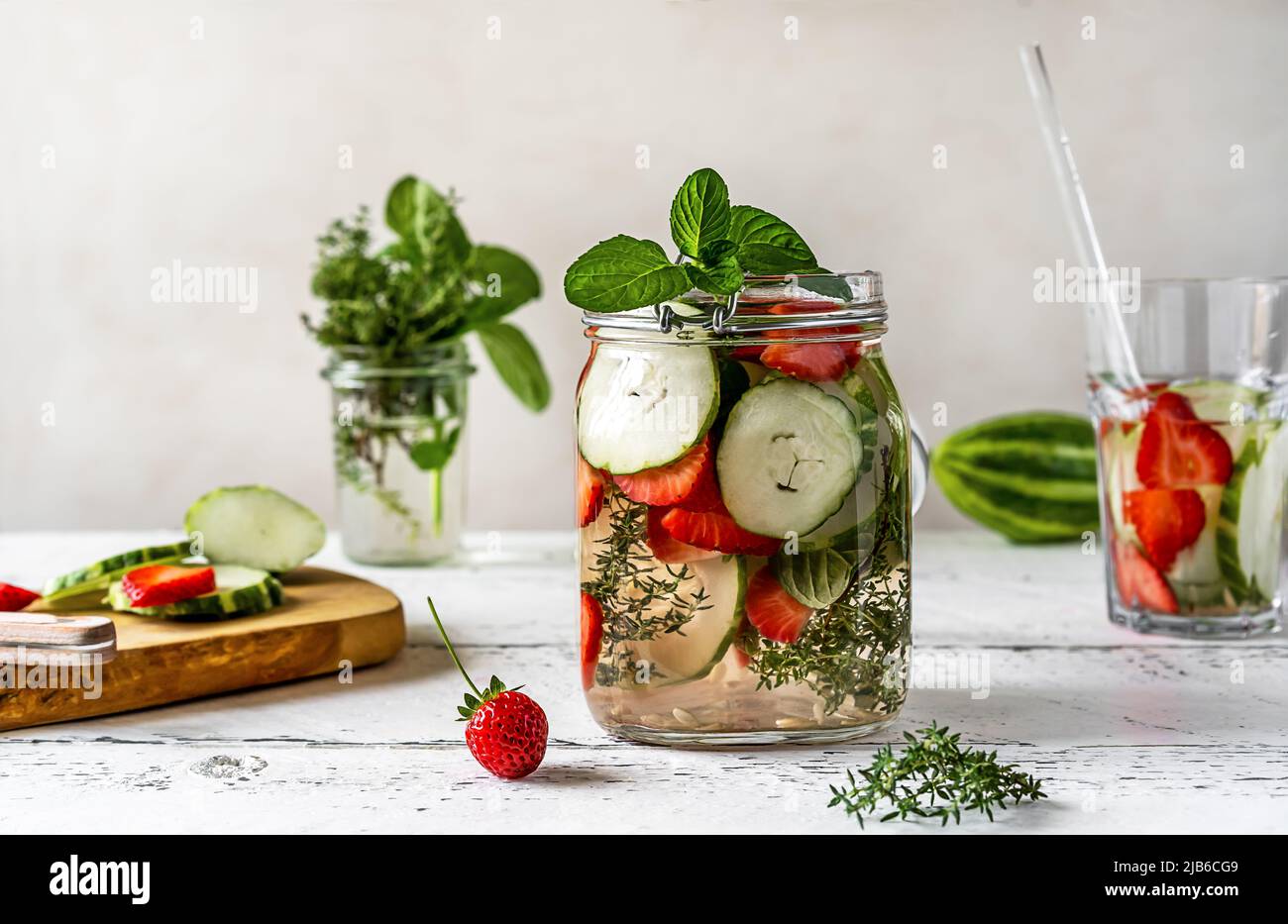 Wasser in Glasgefäß mit Zutaten - Erdbeere, Meloncella, die Hybrid aus Gurke und Melone, Thymian, Minze ist. Stockfoto