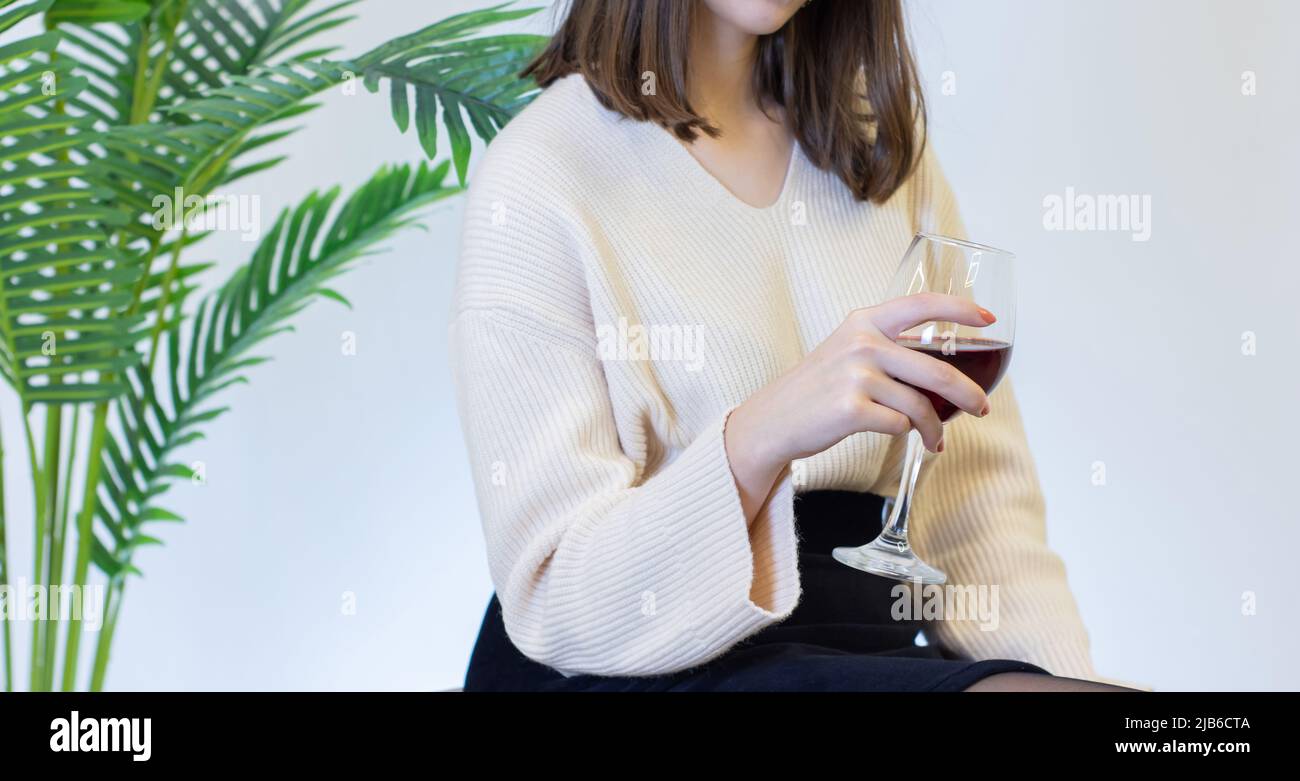 Frau in weißem Kleid trinkt Wein aus einem Weinglas Stockfoto