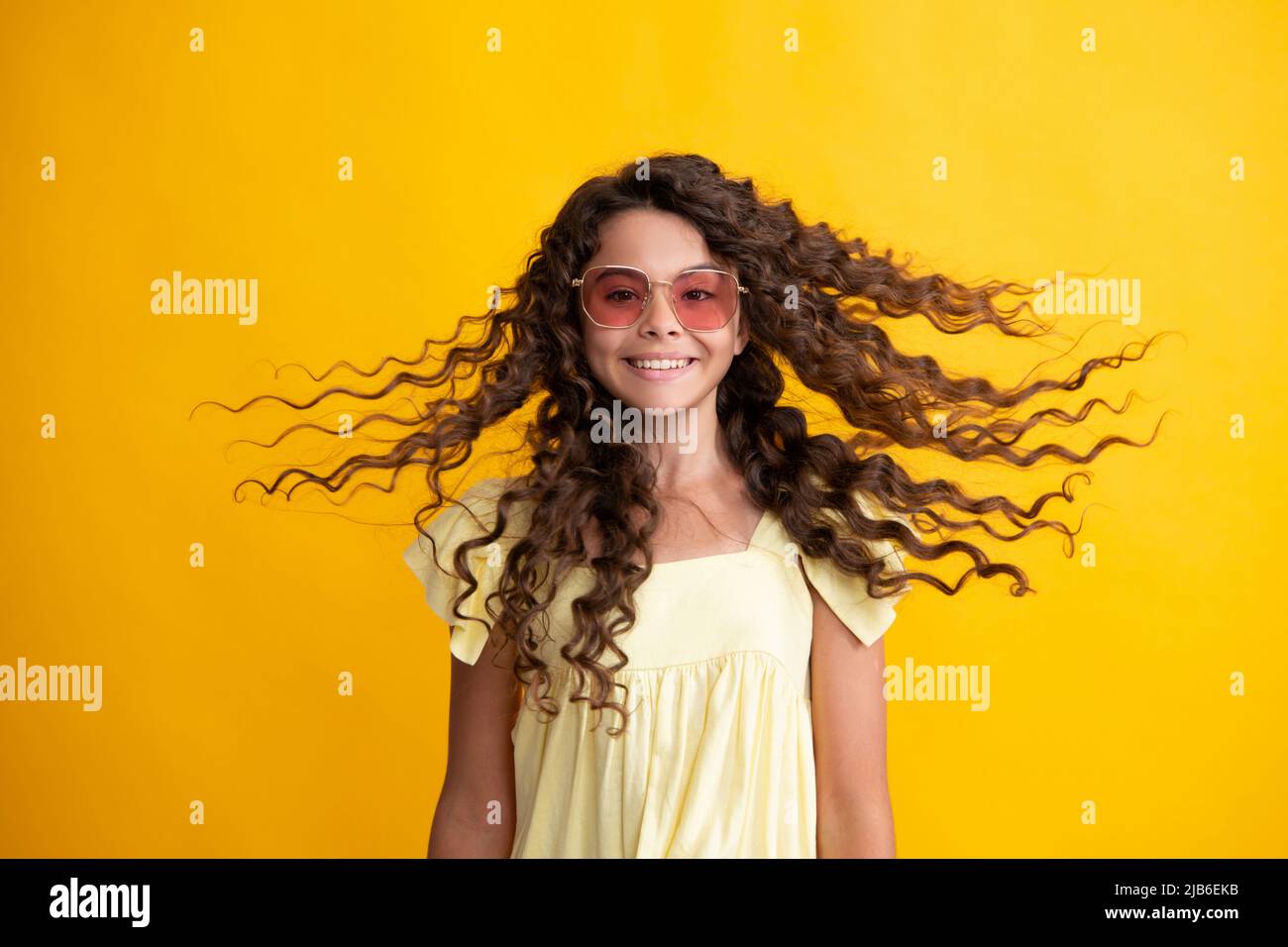 Teenager-Porträt mit verrückten Bewegung Haare. Junge Teenager-Kind mit fließenden Haaren. Brünette teen Mädchen flatternde Haare in Bewegung, isoliert auf gelb Stockfoto
