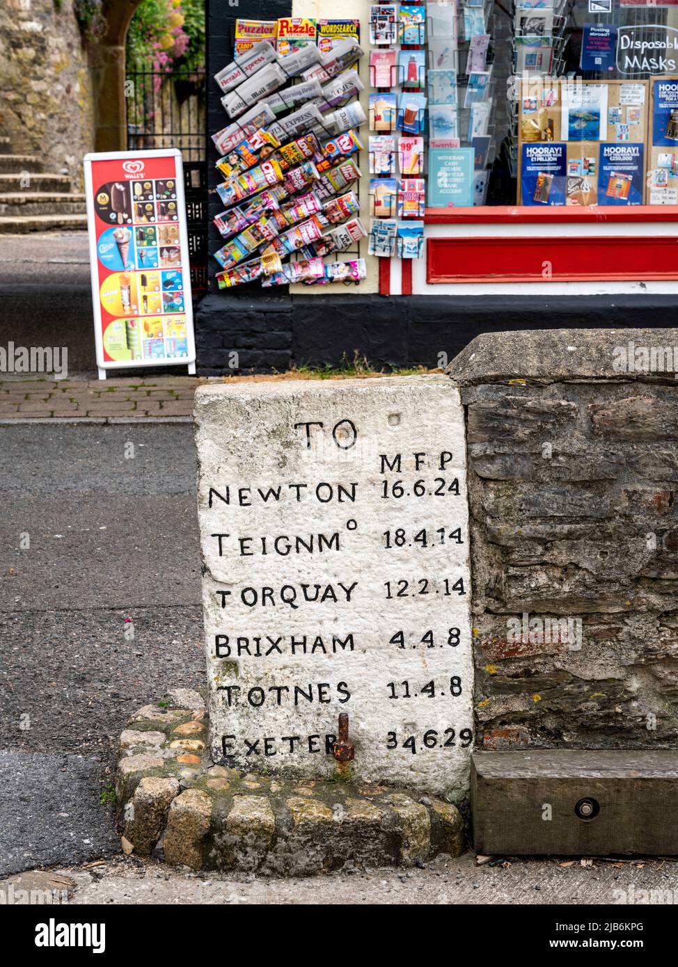 Ein alter Meilenstein in Kingswear, Devon, Großbritannien, der Entfernungen in Meilen, Furlongs und Polen zeigt. Stockfoto