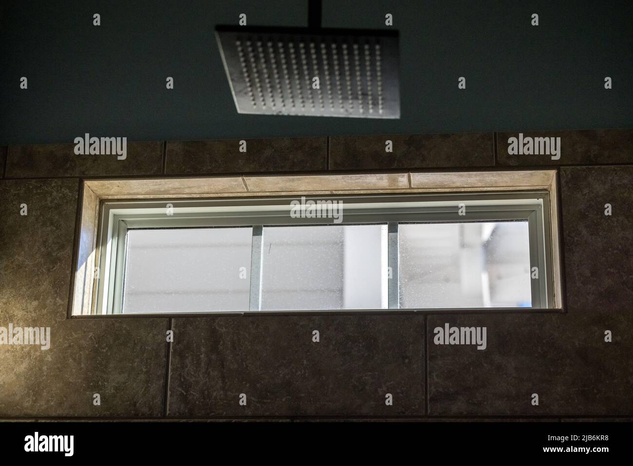 Ein kleines oberes Fenster in einem dunklen Hauptbadezimmer, um mehr Licht hereinzuholen Stockfoto