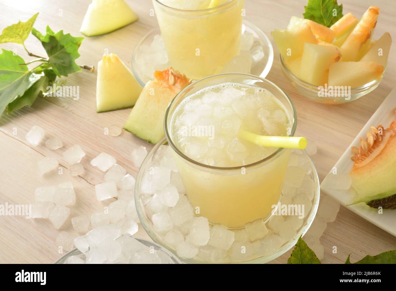 Gläser mit Melone trinken mit Eis auf weißem Holztisch und schneiden Früchte herum. Ansicht von oben. Horizontale Zusammensetzung. Stockfoto
