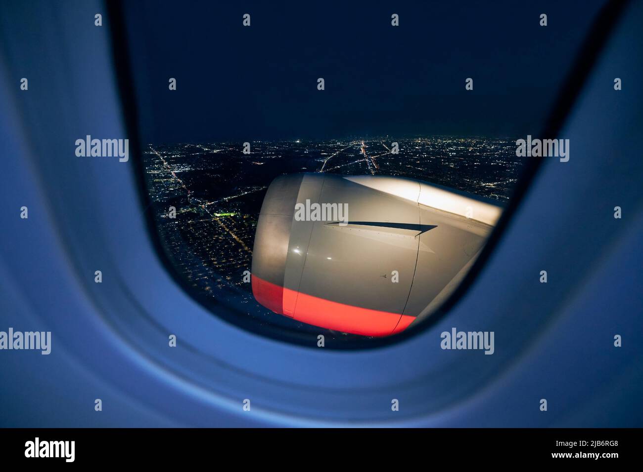 Blick vom Flugzeugfenster beim Start auf die beleuchtete Stadt in der Nacht. Stockfoto