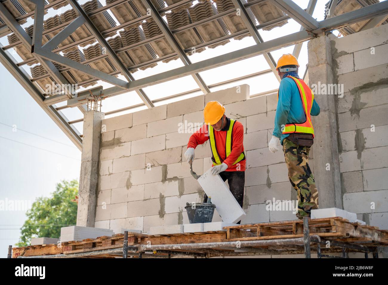 Asian zwei Bauarbeiter verwenden auf der Baustelle Klebemörtel für leichte Mauerarbeiten. Stockfoto