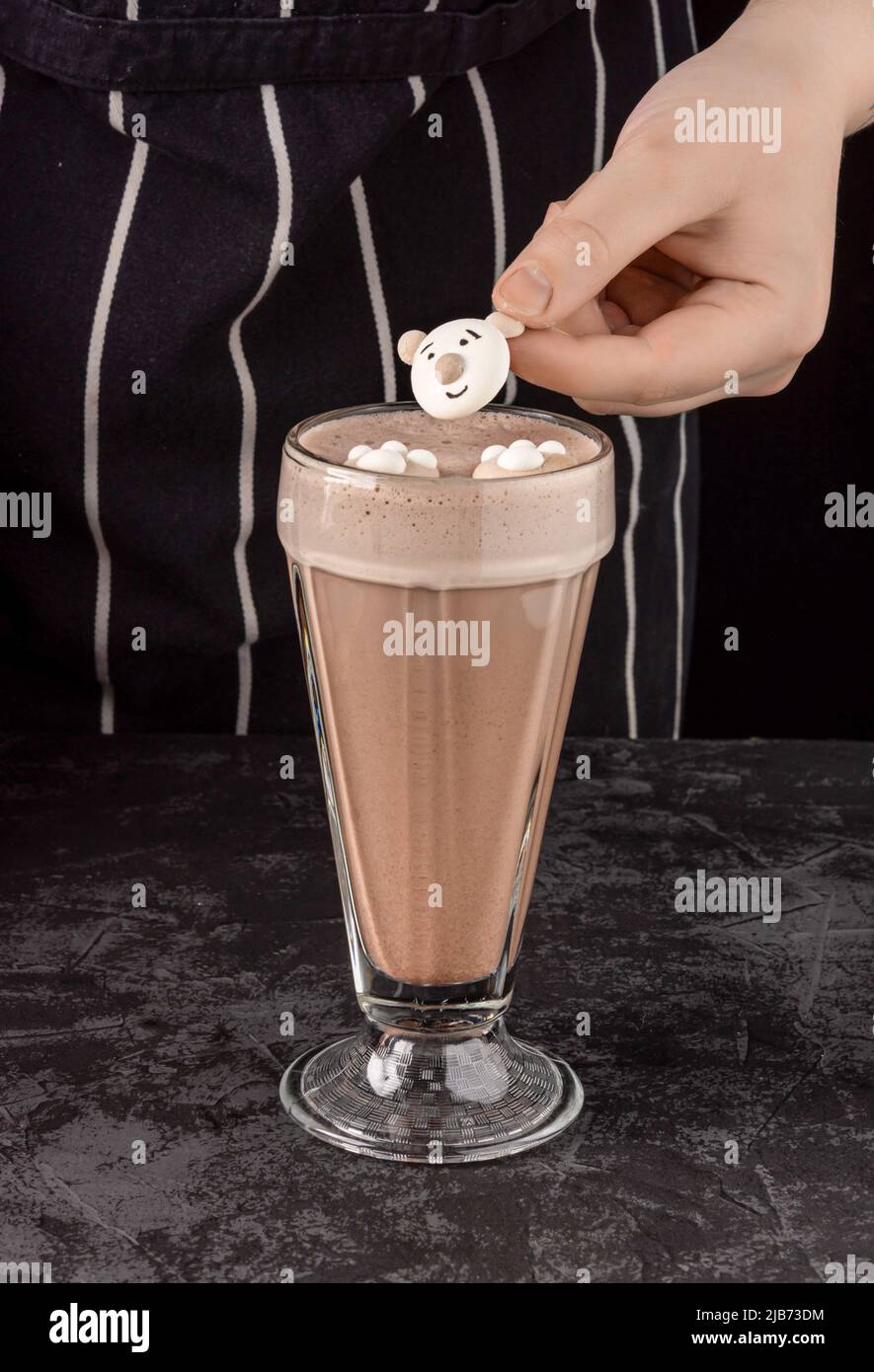 In einem Café auf dunklem Hintergrund ist ein Kakaogetränk mit lustigen Keksen dekoriert Stockfoto