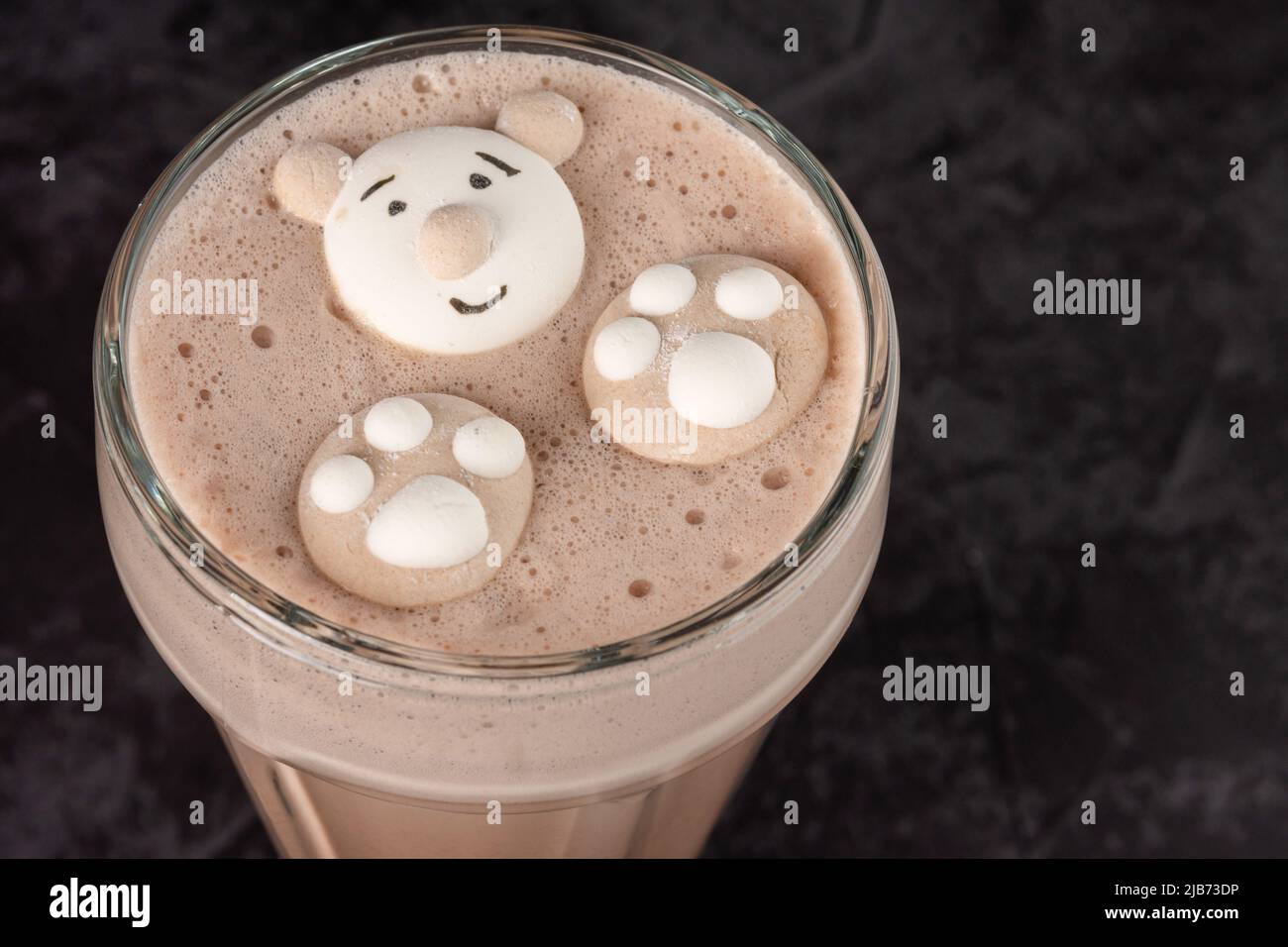 In einem Café auf dunklem Hintergrund ist ein Kakaogetränk mit lustigen Keksen dekoriert Stockfoto