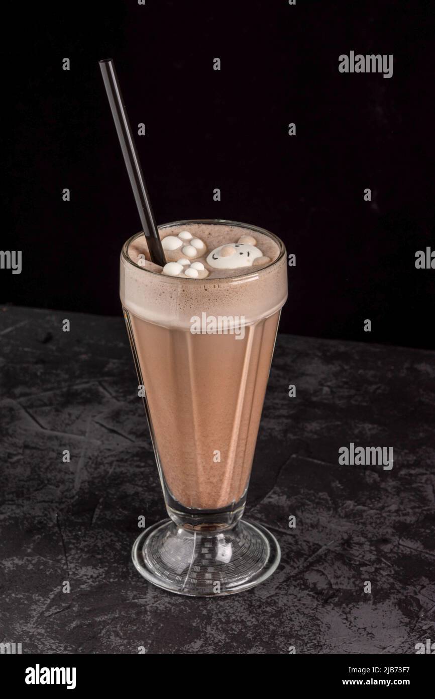 In einem Café auf dunklem Hintergrund ist ein Kakaogetränk mit lustigen Keksen dekoriert Stockfoto